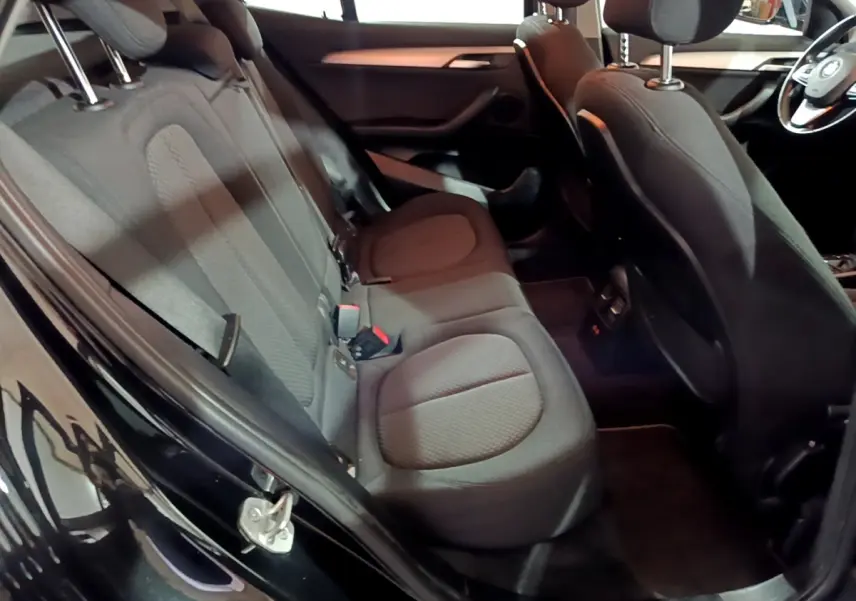 Vue intérieure côté gauche montrant la banquette arrière noire et les sièges avant du BMW X2 sDrive18i Lounge 2023.
