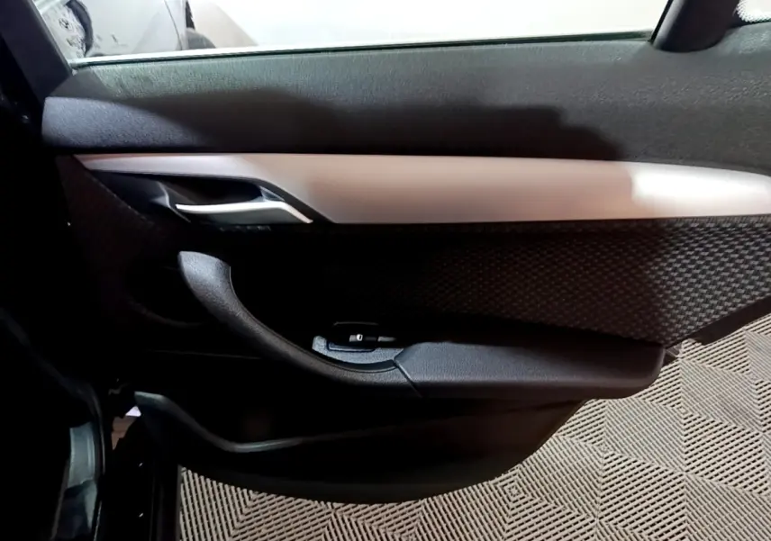 Gros plan sur la porte côté gauche intérieure noire avec insert argenté de la BMW X2 sDrive18i Lounge 2023.