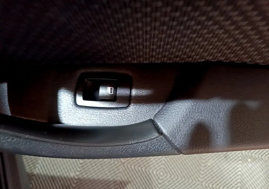 Détail de la commande de lève-vitre noir sur la porte intérieure d'une BMW X2 sDrive18i Lounge 2023.