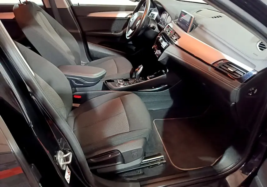 Intérieur avant droit de la BMW X2 sDrive18i Lounge 2023 noir, avec tableau de bord et console centrale visibles.