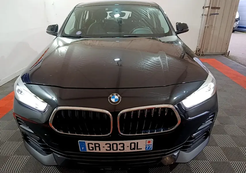 Vue frontale d’un BMW X2 noir 2023 avec phares LED allumés et calandre double haricot caractéristique.