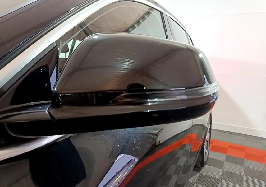 Gros plan sur le rétroviseur côté conducteur noir brillant du BMW X2 sDrive18i Lounge 2023, reflet visible.