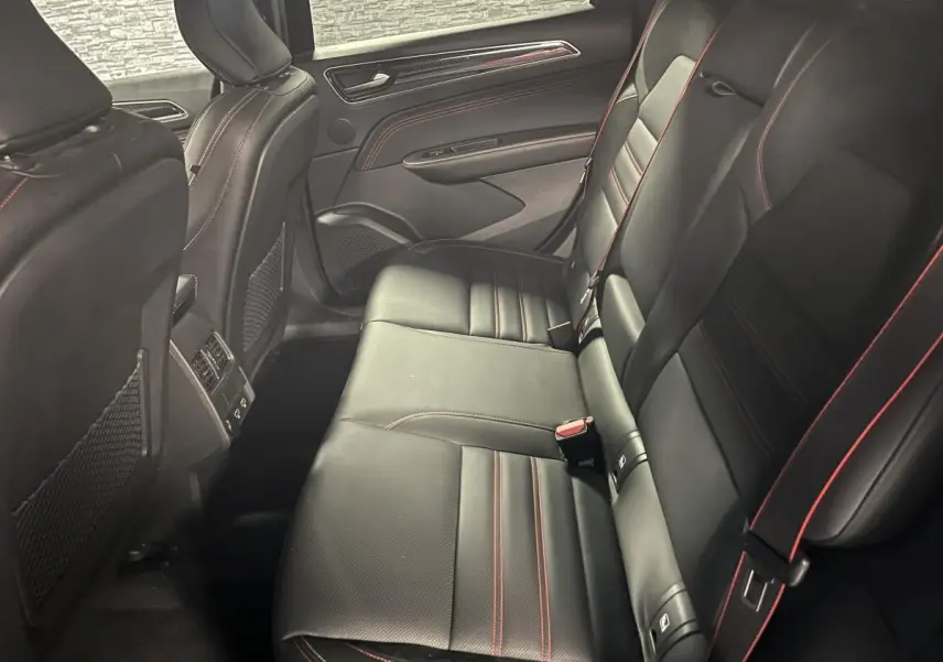 Vue latérale intérieure arrière du Renault Arkana 2023 noir avec sellerie cuir/suédine et surpiqûres rouges.