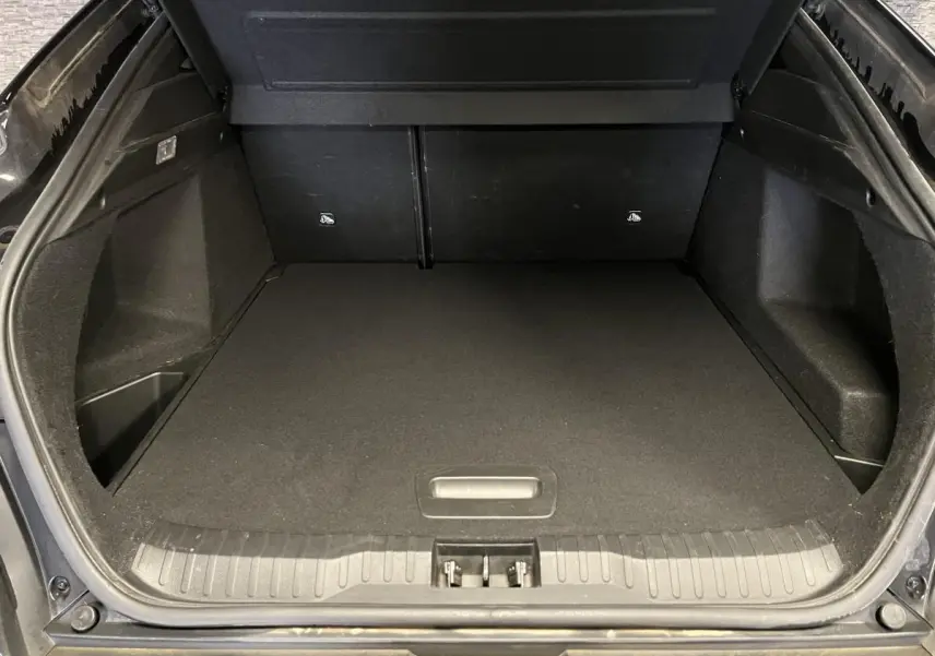 Coffre ouvert vu de l'arrière d'un Renault Arkana noir 2023, espace de chargement vide et tapis noir.