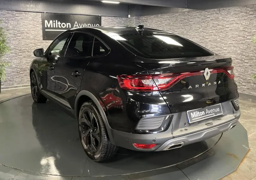 Vue 3/4 arrière droite du Renault Arkana noir brillant avec feux arrière reliés et jantes noires sport R.S. Line.