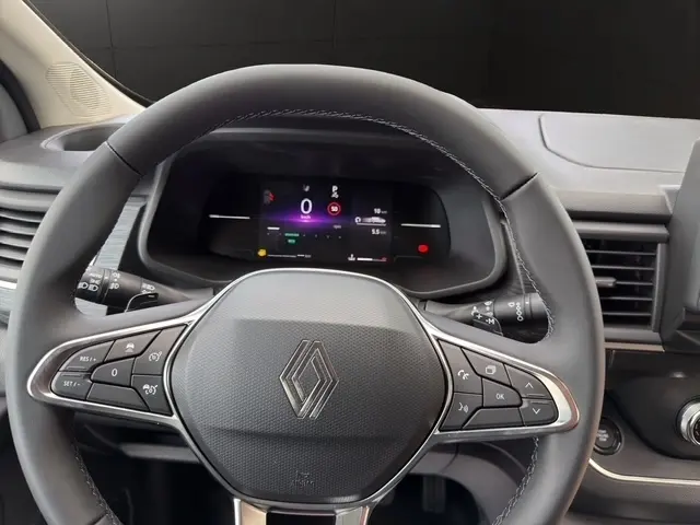Vue rapprochée du volant multifonctions noir et du tableau de bord numérique du Renault Trafic Fourgon gris foncé.
