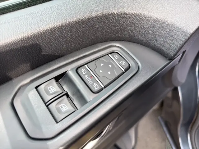 Gros plan sur les commandes de réglage des rétroviseurs et des vitres côté conducteur du Renault Trafic Fourgon gris foncé.