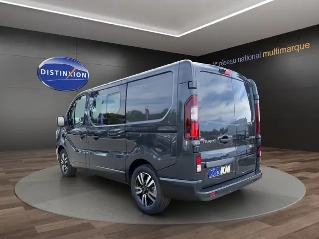 Renault Trafic Fourgon gris foncé en 3/4 arrière droit, avec vitres teintées et jantes alliage noires.