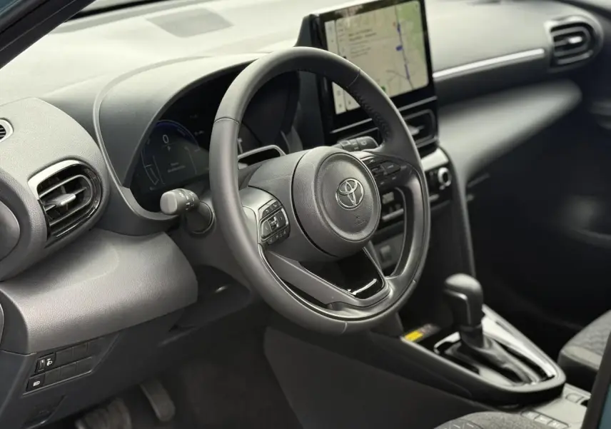 Vue intérieure côté conducteur de la Toyota Yaris Cross 2026, volant cuir et écran tactile central visible.