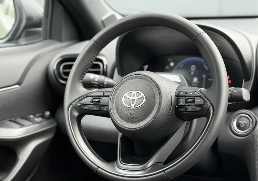 Vue rapprochée du volant cuir noir de la Toyota Yaris Cross 1.5 Hybrid 116 Design avec commandes intégrées.