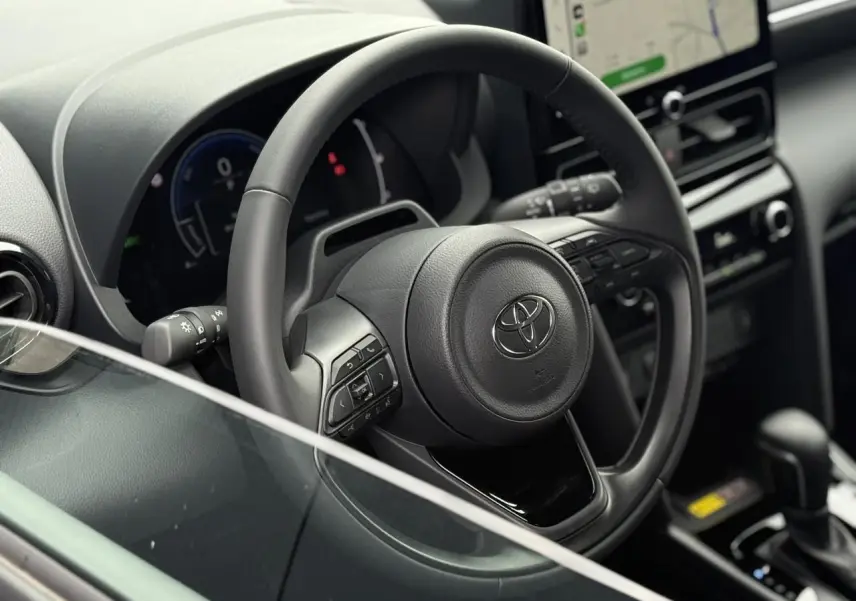 Vue intérieure rapprochée du volant cuir noir et tableau de bord de la Toyota Yaris Cross 1.5 Hybrid 2026.
