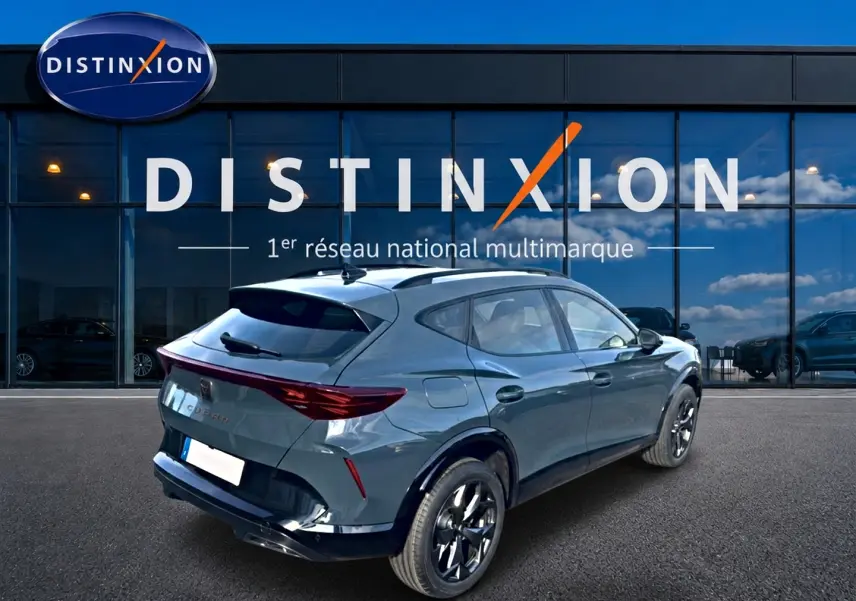 Vue 3/4 arrière droite d'un CUPRA Formentor bleu fjord avec jantes noires, garé devant une vitrine Distinxion.