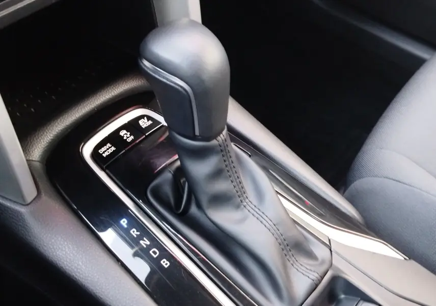 Gros plan sur le levier de vitesses automatique noir de la Toyota Corolla Cross 1.8 140ch Dynamic, intérieur gris.
