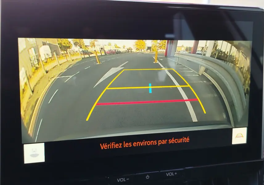 Vue de la caméra de recul du Toyota Corolla Cross gris minéral, affichant les lignes de guidage sur un parking extérieur.
