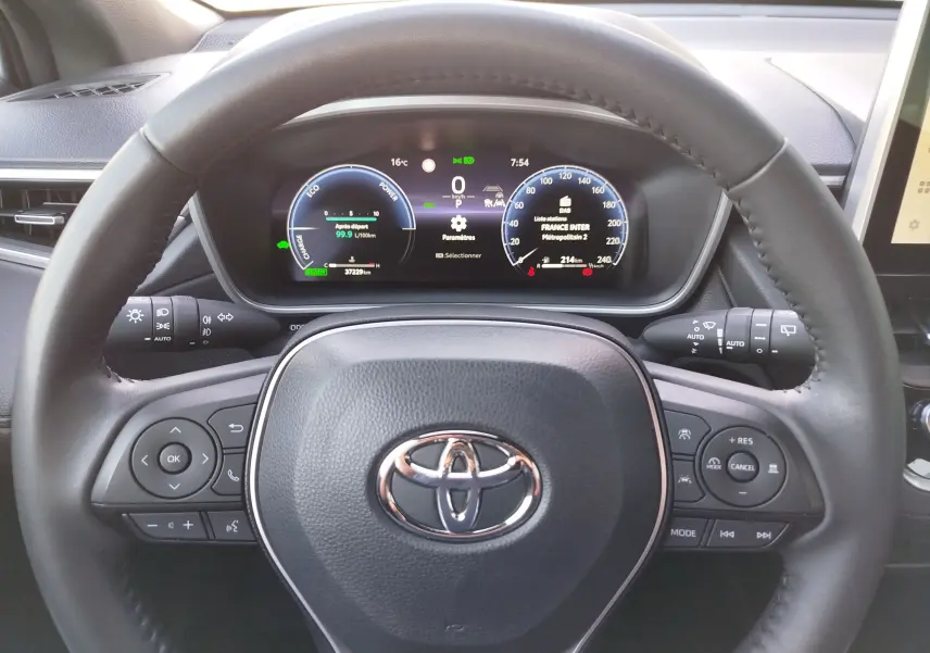 Vue centrée sur le volant noir avec logo Toyota et tableau de bord numérique du Corolla Cross gris minéral 2025.