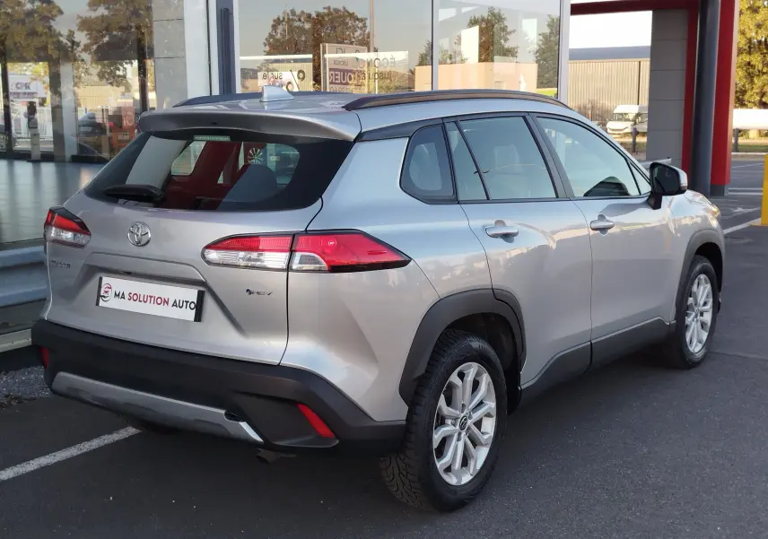 Vue 3/4 arrière droite du Toyota Corolla Cross gris minéral avec jantes alliage et feux arrière LED visibles.