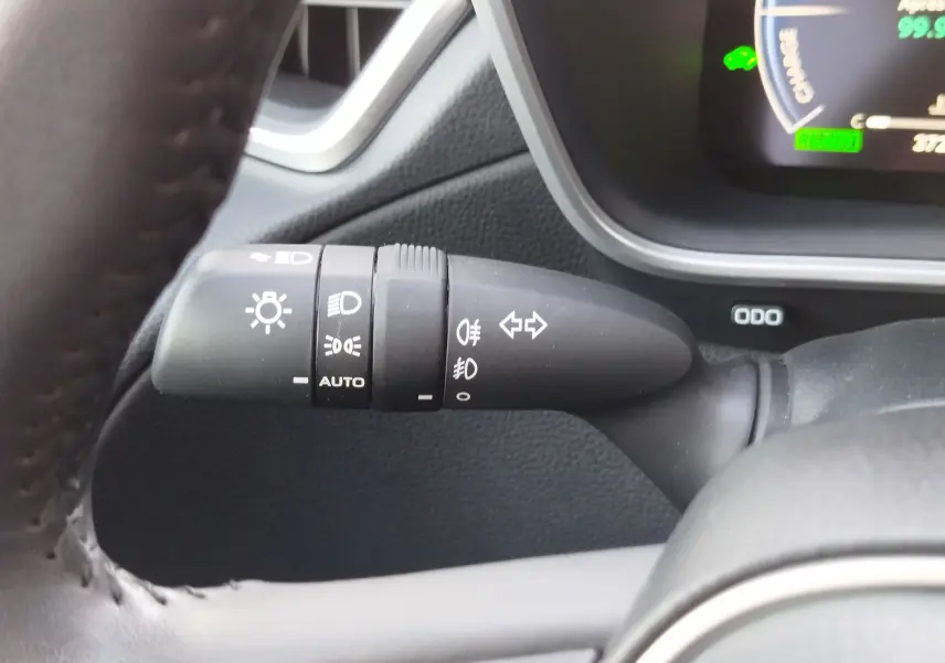 Gros plan sur la commande des feux et clignotants à gauche du volant dans le Toyota Corolla Cross gris minéral 2025.