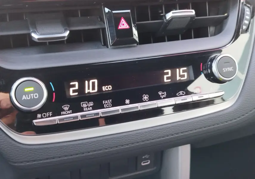 Gros plan sur la console centrale de la Toyota Corolla Cross 2025, affichant la climatisation automatique avec réglages numériques.