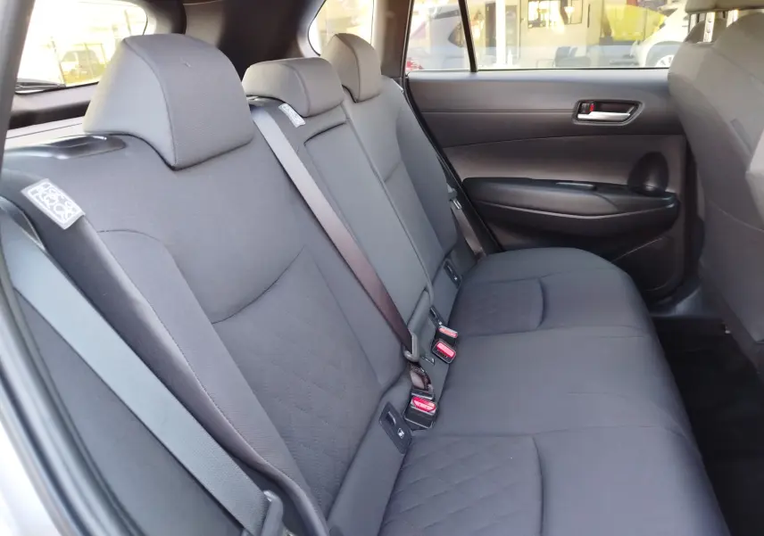 Vue intérieure côté droit des sièges arrière gris tissu de la Toyota Corolla Cross 2025, avec ceintures de sécurité visibles.