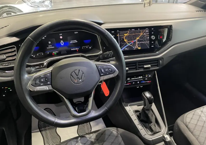 Vue intérieure avant du tableau de bord et volant cuir multifonction d'une Volkswagen Polo 2024 blanche, avec écran tactile et levier de boîte auto.