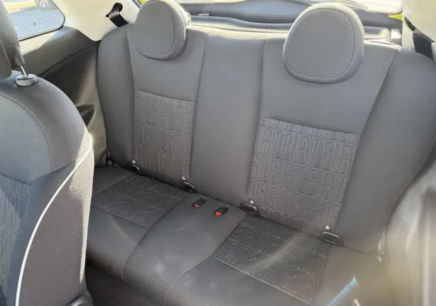 Vue intérieure de la banquette arrière noire avec motifs monogramme Fiat d'une FIAT 500 e jaune, côté droit visible.