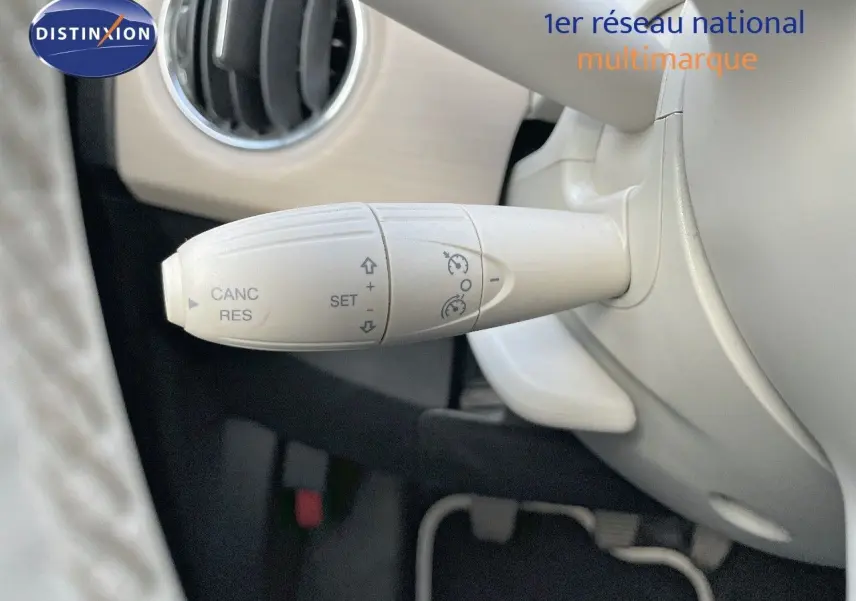 Gros plan sur la commande de régulateur de vitesse blanc dans l'habitacle clair d'une Fiat 500 blanche 2022.