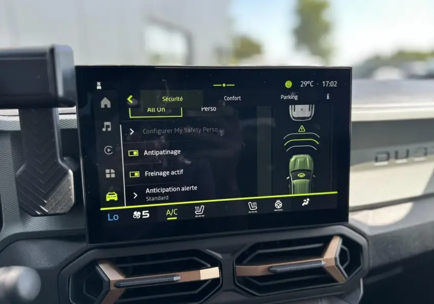 Écran tactile central du Dacia Duster 2025 affichant les réglages de sécurité et confort, tableau de bord gris clair.