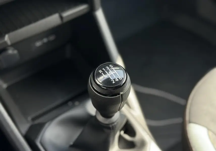 Gros plan sur le levier de vitesses manuel du Dacia Duster 2025, finition Gris Schiste, intérieur sombre.