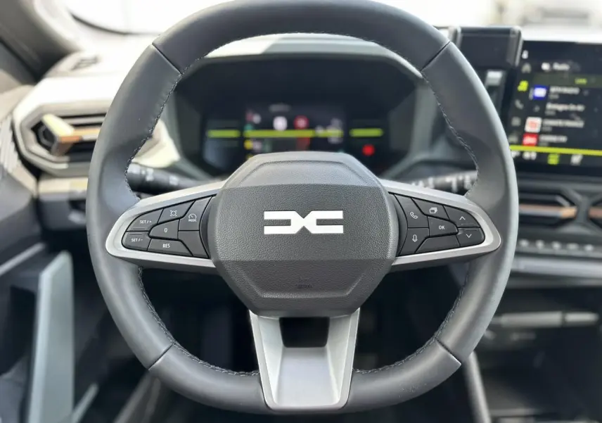 Volant cuir noir du Dacia Duster 2025 ECO-G 100 Extrême avec commandes intégrées et tableau de bord digital flou en arrière-plan.