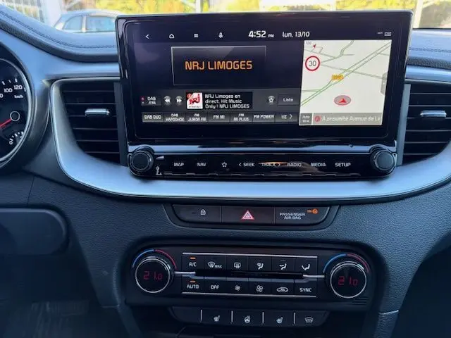 Tableau de bord de la Kia CEE'D 2024 avec écran tactile affichant la radio NRJ Limoges et commandes climatisation digitales.