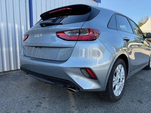 Vue 3/4 arrière droite d'une KIA CEE'D 2024 argent lunaire avec feux LED et sortie d'échappement chromée visible.