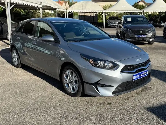 KIA CEE'D argent lunaire vue 3/4 avant droit sur parking avec calandre noire et phares LED marqués.