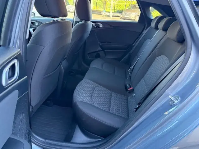 Vue intérieure arrière côté droit de la Kia CEE'D 2024 argent lunaire, sièges tissu gris avec motifs géométriques et ceintures visibles.