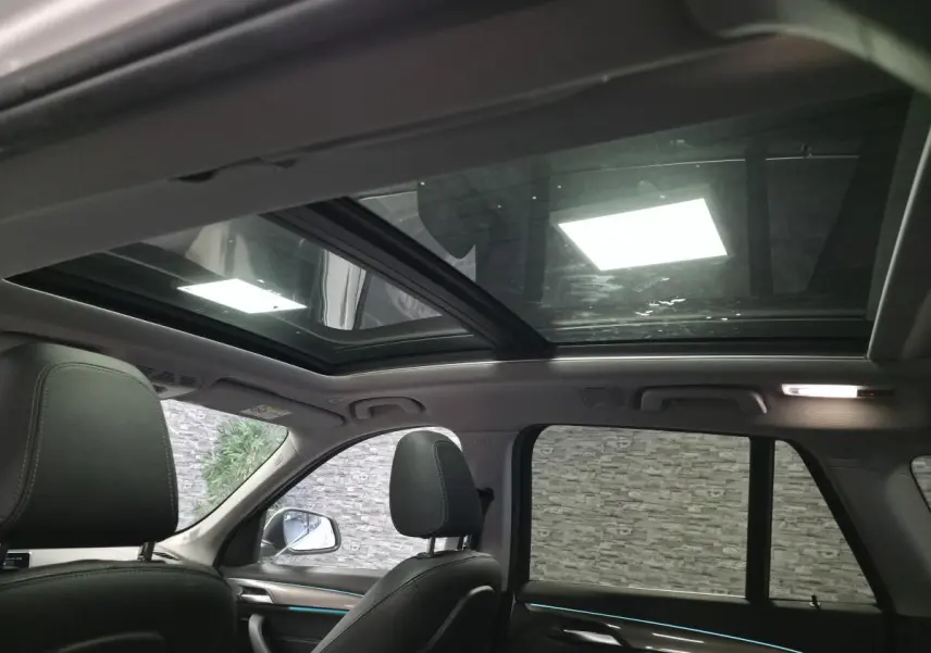Vue intérieure arrière montrant les sièges noirs et le toit panoramique vitré du BMW X1 sDrive 18d blanc.
