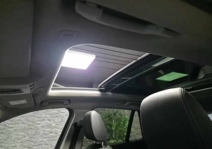 Vue intérieure du toit ouvrant panoramique et appuie-tête avant du BMW X1 blanc sDrive 18d xLine 2022.