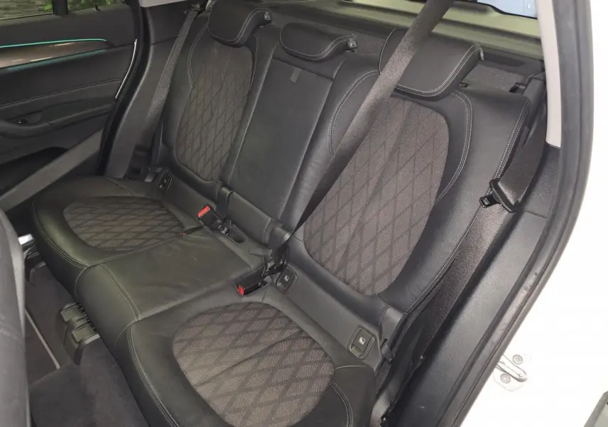 Vue intérieure côté droit sur la banquette arrière en cuir et tissu noir à motifs du BMW X1 sDrive 18d blanc 2022.