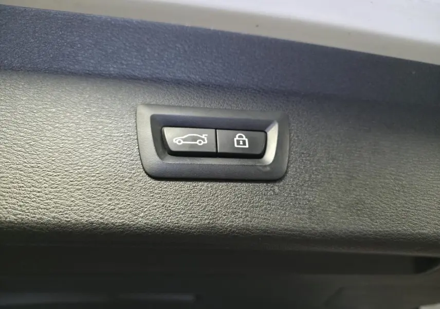 Boutons de déverrouillage et fermeture électrique du hayon sur le bord intérieur d’un BMW X1 blanc.
