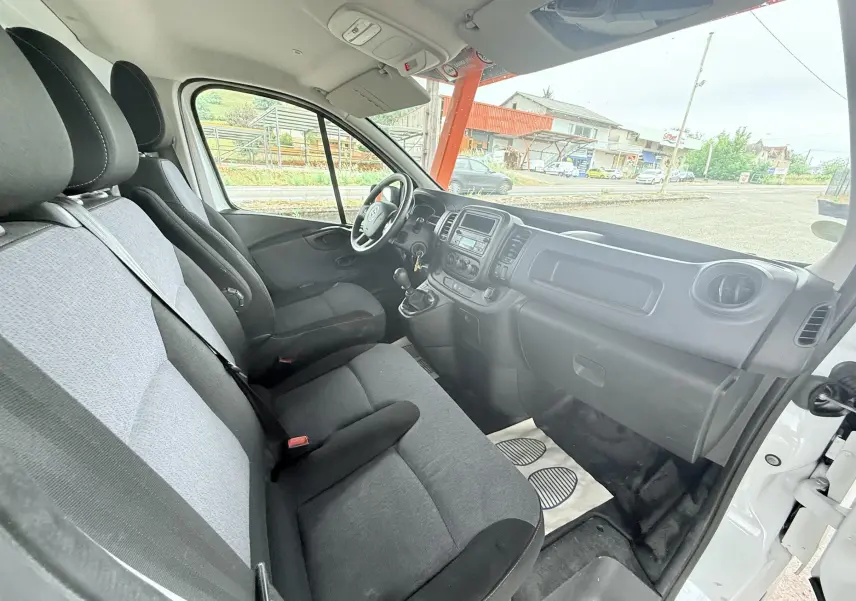 Vue intérieure côté passager de l'Opel Vivaro blanc 2018, montrant les sièges gris et la planche de bord noire.