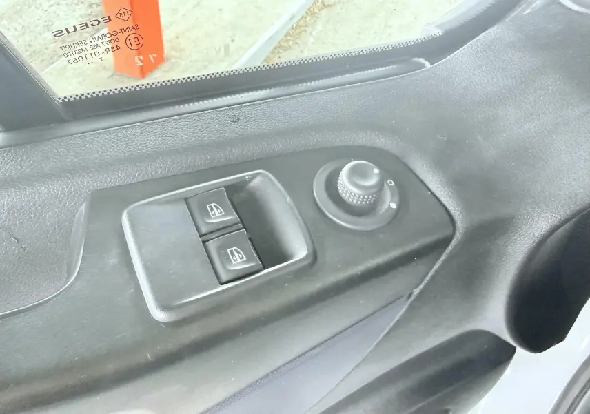 Gros plan sur les commandes de lève-vitres et réglage des rétroviseurs côté conducteur d’un Opel Vivaro blanc.