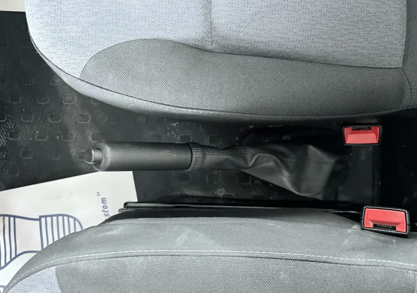 Vue intérieure centrée sur le frein à main entre les sièges avant gris du véhicule Opel Vivaro blanc.