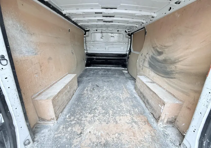 Vue intérieure arrière du fourgon blanc Opel Vivaro 2018, montrant la zone de chargement avec parois en bois usées.