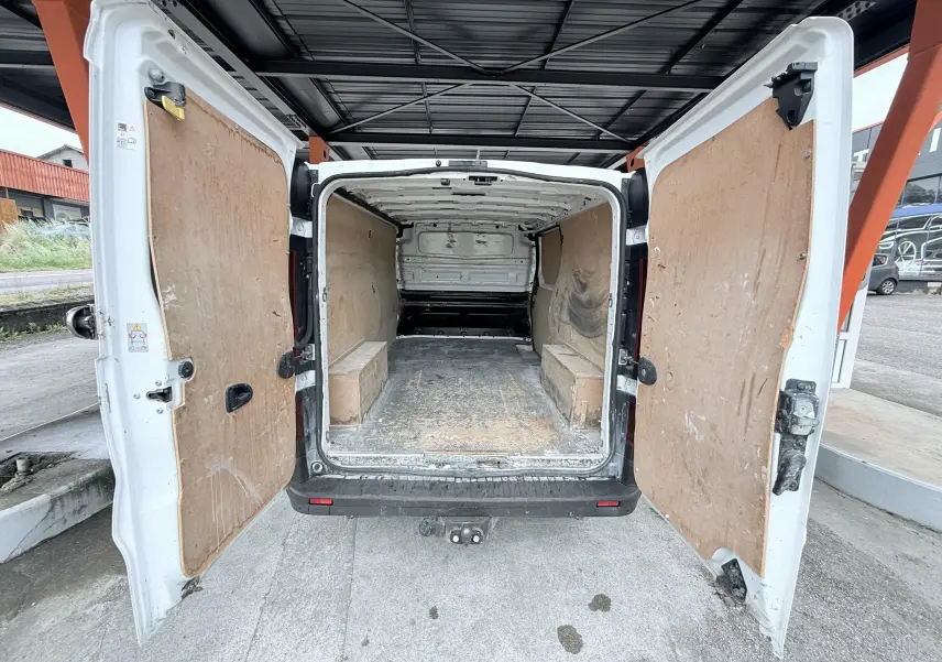 Vue arrière avec portes ouvertes d'un Opel Vivaro blanc 2018 montrant l'espace de chargement vide et protégé par des panneaux en bois.