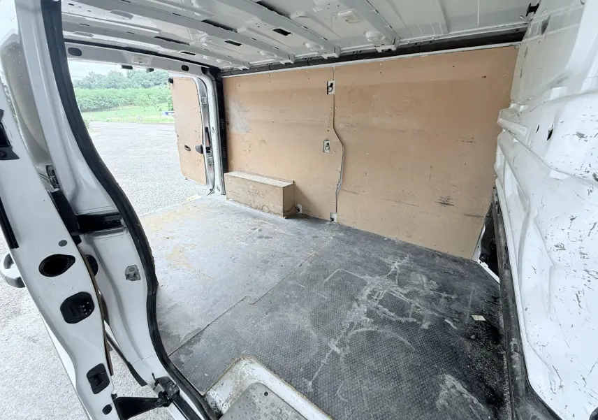 Vue intérieure arrière du fourgon blanc Opel Vivaro 2018, montrant l’espace de chargement avec parois en bois et sol usé.