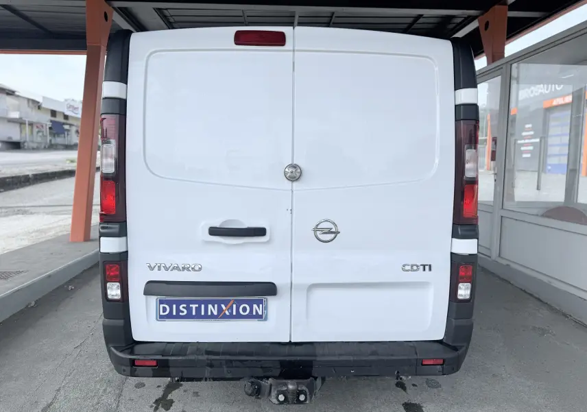 Vue arrière d’un Opel Vivaro blanc avec hayon fermé et attelage visible sous le pare-chocs noir.