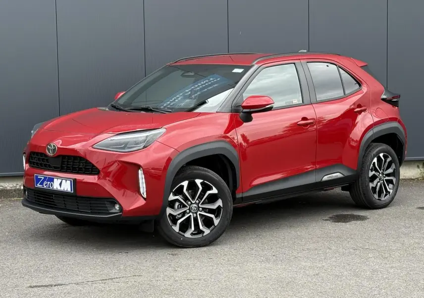 Toyota Yaris Cross rouge intense en 3/4 avant droit, avec jantes alliage et protections noires sur les passages de roue.