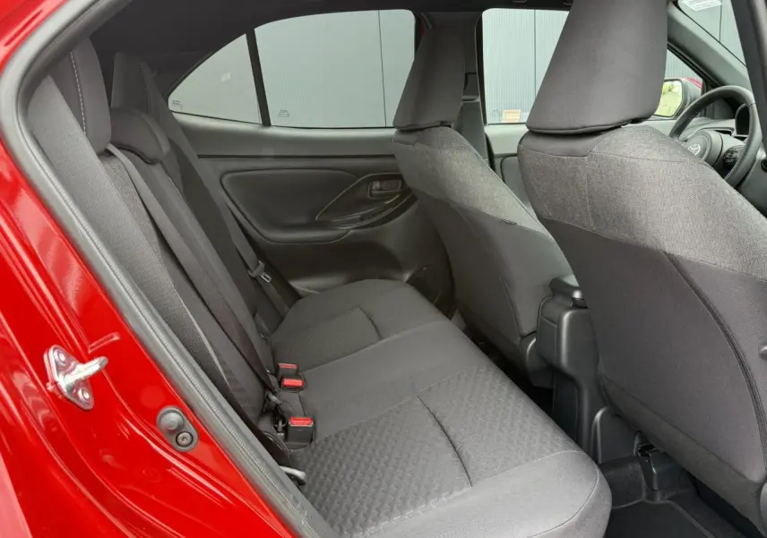 Vue intérieure côté gauche sur les sièges arrière gris d’une Toyota Yaris Cross 1.5 Hybrid rouge intense 2026.