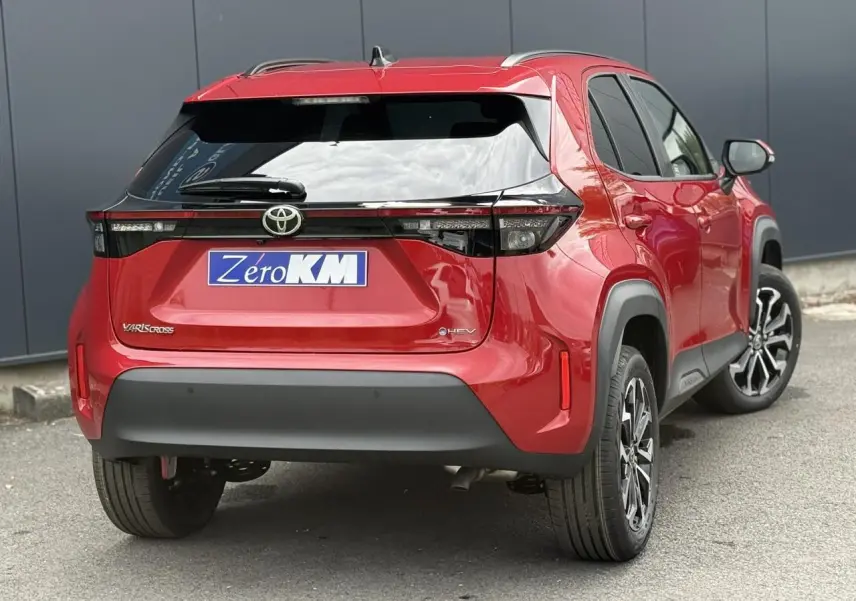 Vue 3/4 arrière droite d'une Toyota Yaris Cross rouge intense avec feux arrière LED et jantes alliage noires.