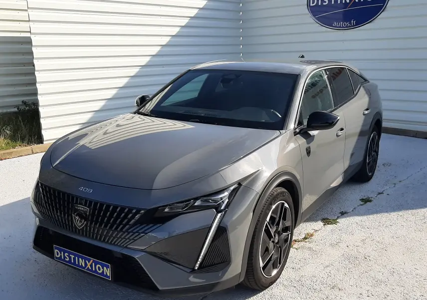 Peugeot 408 gris selenium vue 3/4 avant droit, avec calandre noire distinctive et jantes bi-ton.