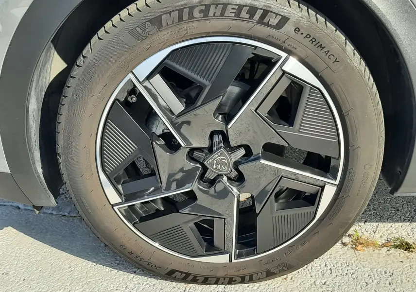 Gros plan sur la roue avant droite d’une Peugeot 408 gris selenium avec jante noire et argentée au design géométrique.