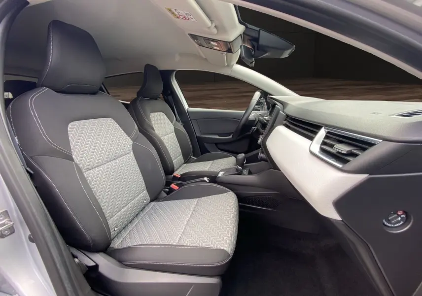 Intérieur avant de la Renault Clio V gris Highland, sièges tissu noir et gris avec motifs, tableau de bord clair moderne.